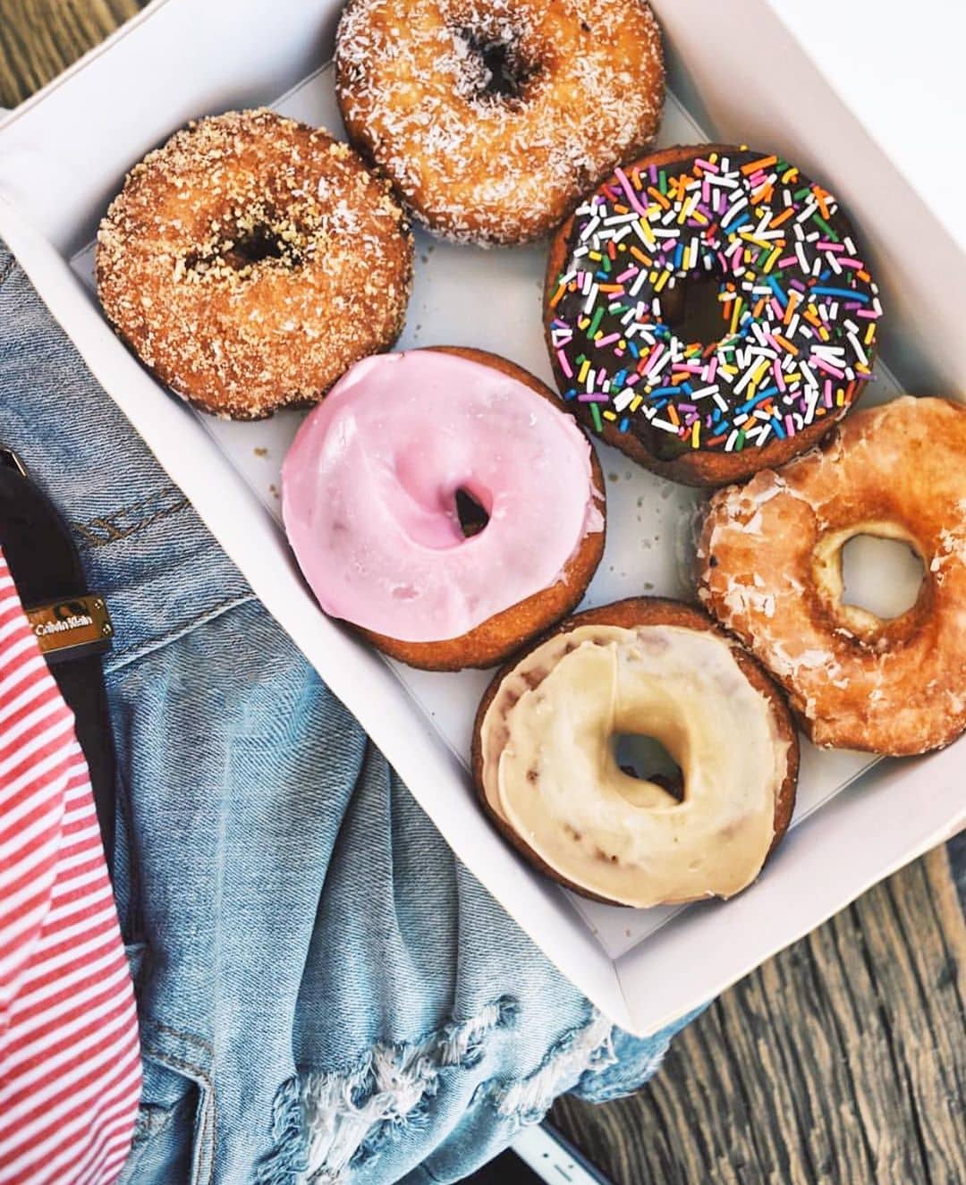 box of donuts that are colourful and sprinkles