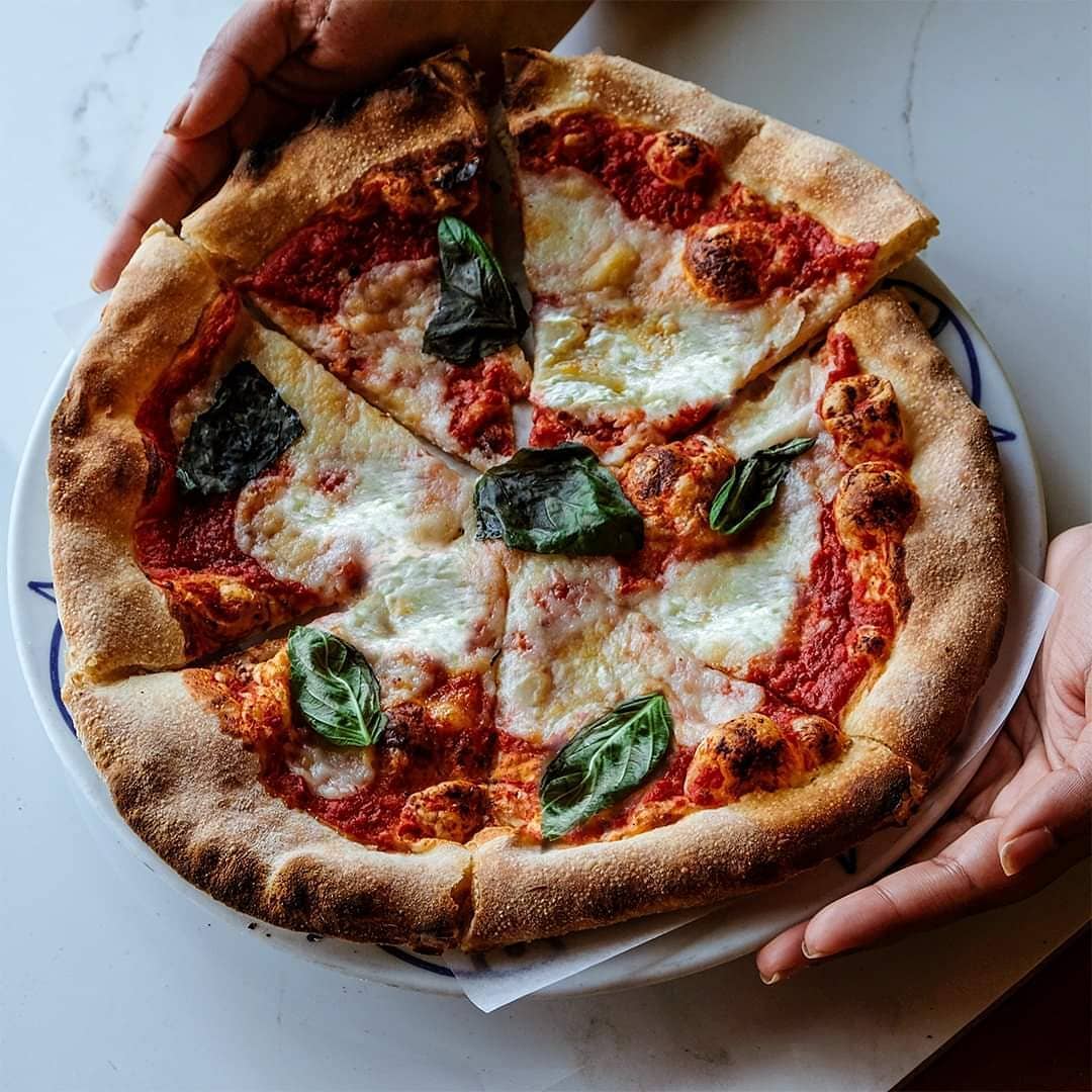 margherita pizza held in hands