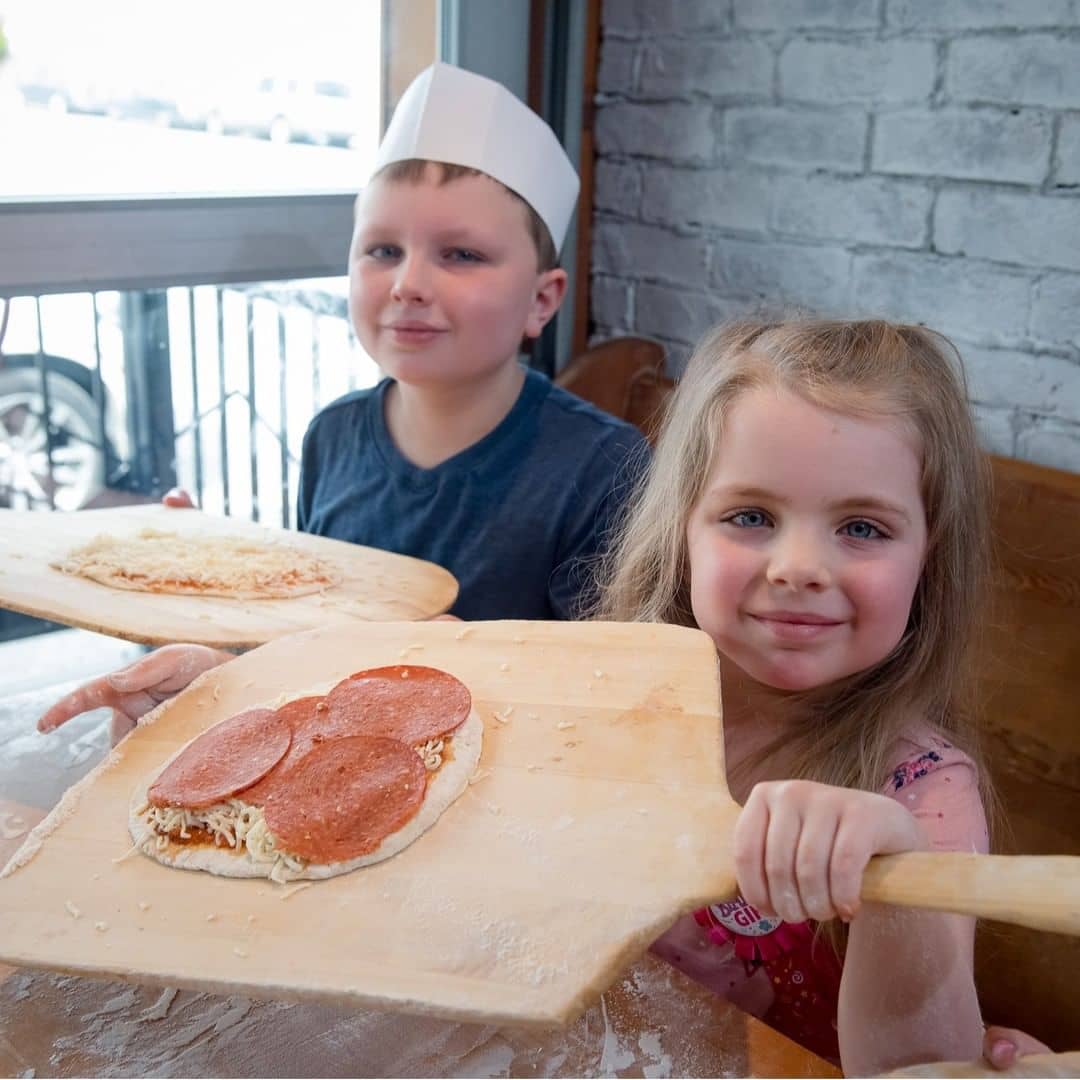 Vancouver kid friendly activities - pizza making rocky mountain flatbread class with two kids showing their progress