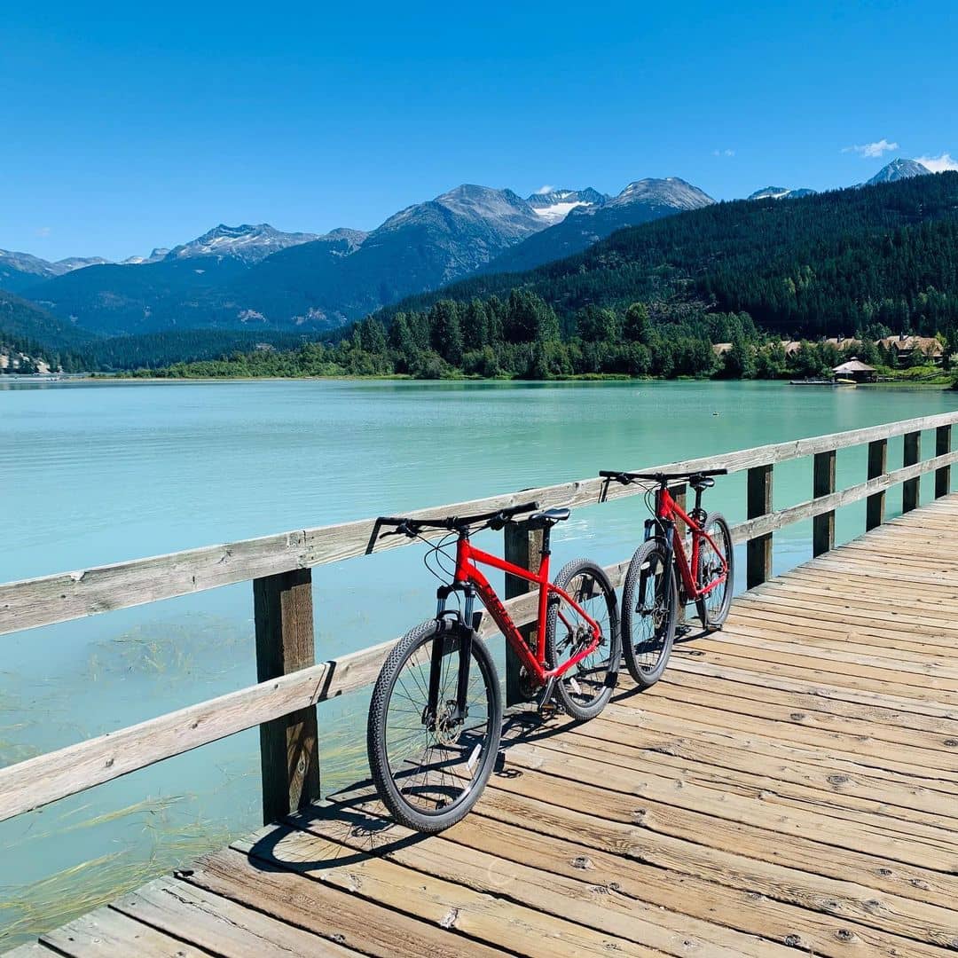 vancouver to whistler - whistler valley trail way of two bikes on a bridge with river and mountain view