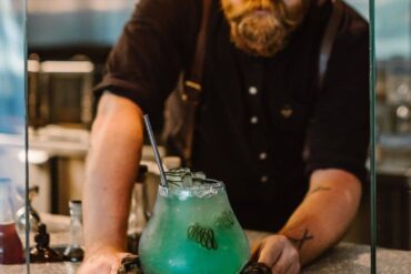 10 Best Cocktail Bars In Vancouver - botanist dining cocktail of deep cove with bartender handing drink