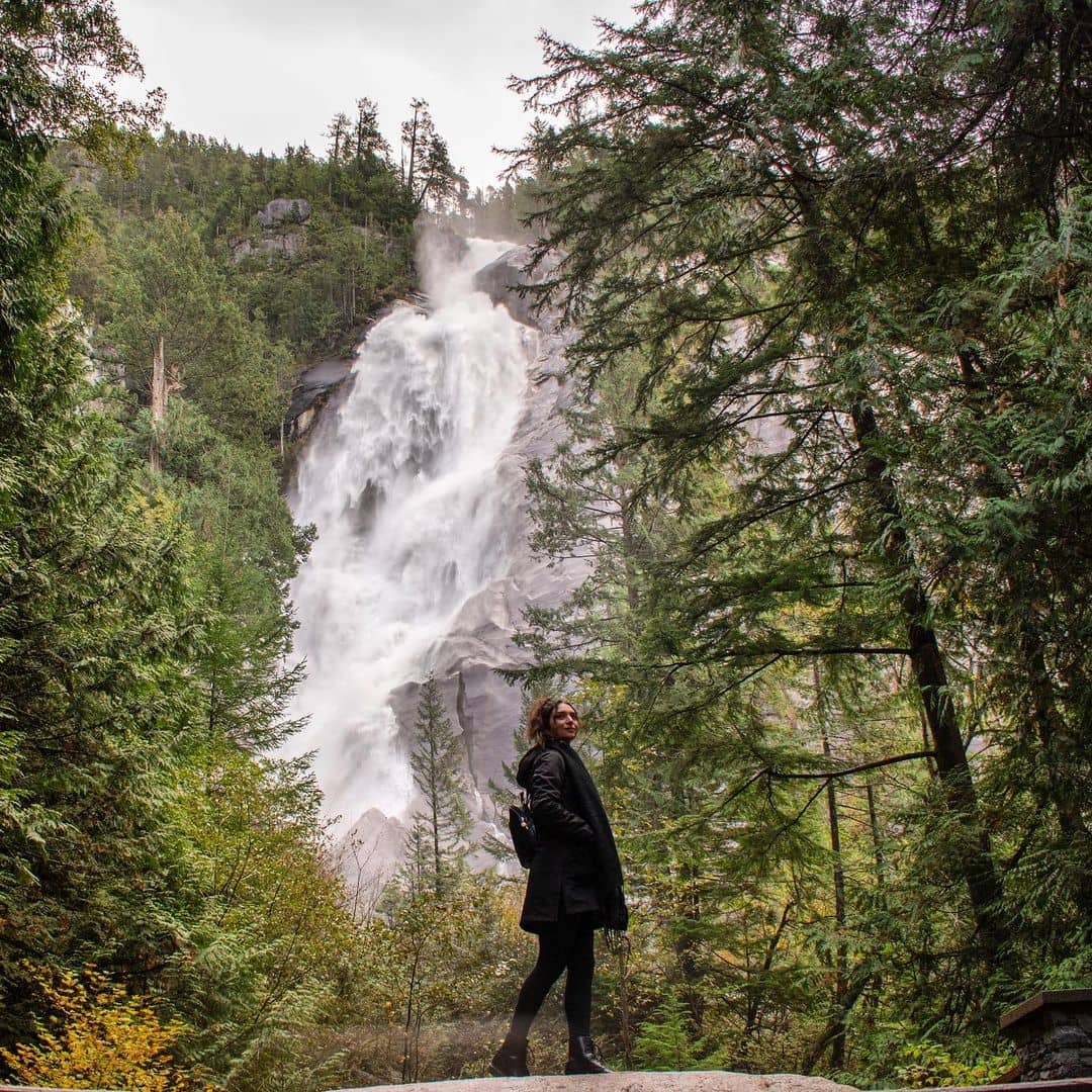 Sea to Sky Highway Guide - Shannon Falls in background with girl in foreground with tress surrounding