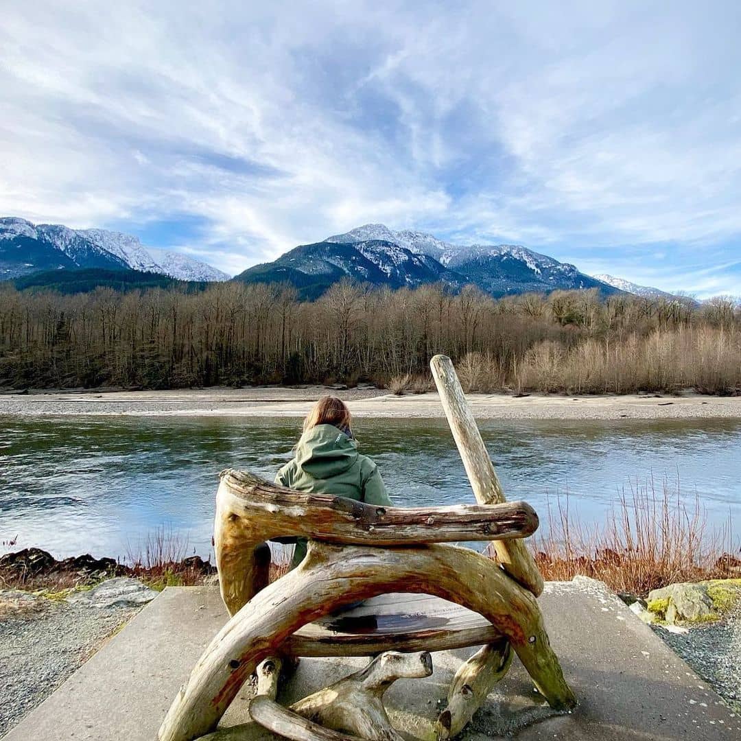 Sea to Sky Highway Guide - Squamish mountain and water view with girl sitting in chair made of tree barks