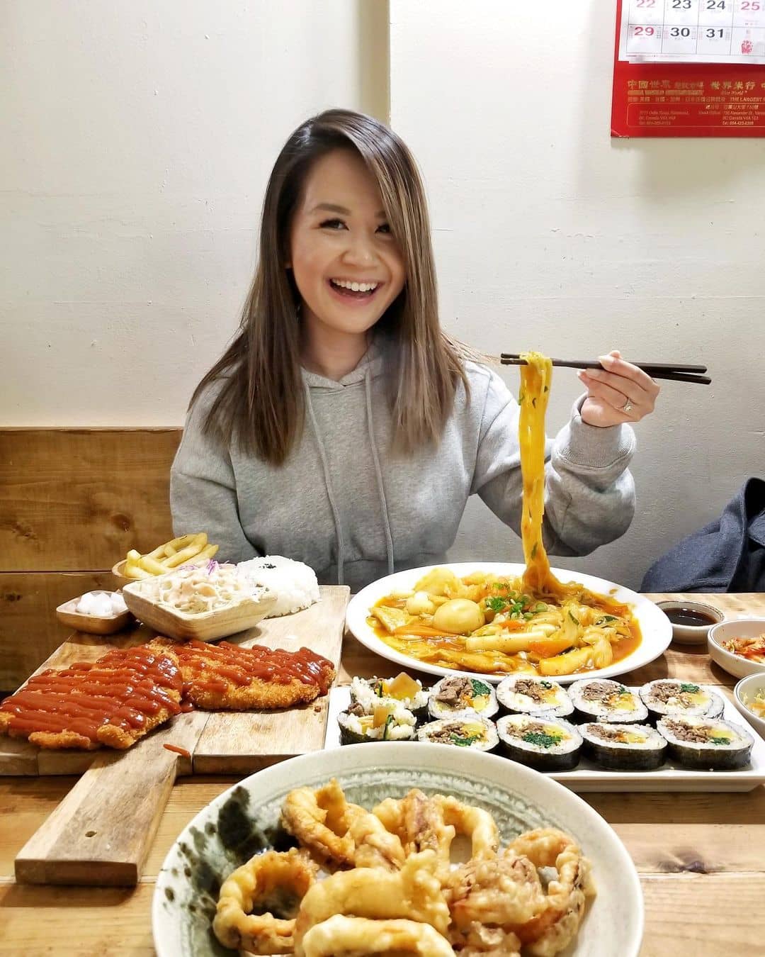 best korean restaurant in richmond - samsoonie noodle and rice with food on table and girl lifting noodle with chopstick