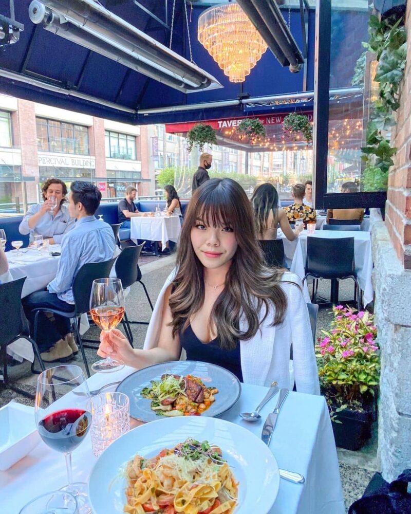 girl sitting behind white cloth table with food ontop in patio setting best yaletown brunch spot brix and mortar